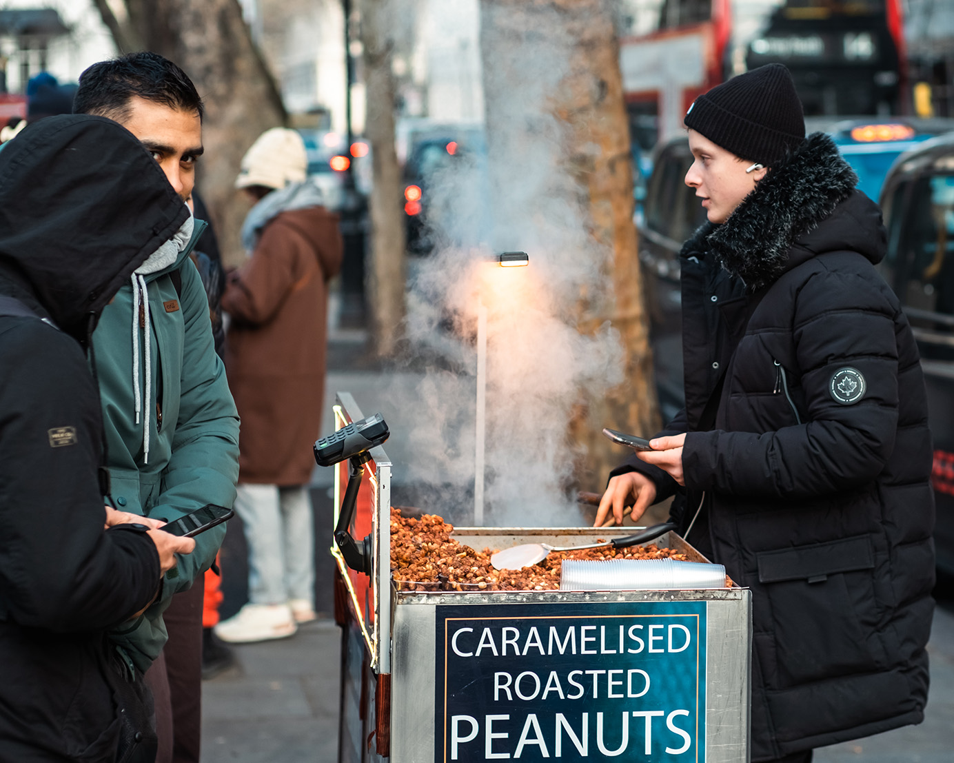 Young person cook roasted peanuts in London, winter.