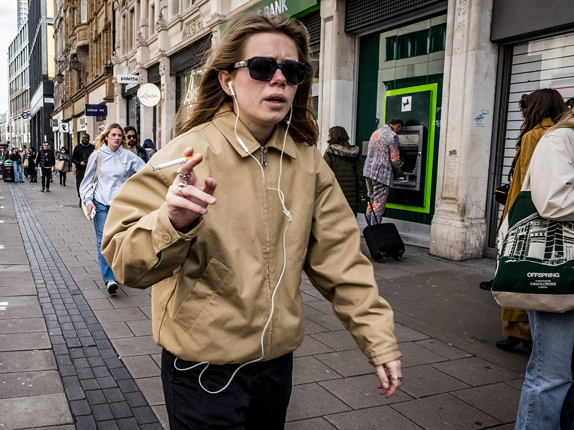 Smoking person walks quickly down Oxford street, London.