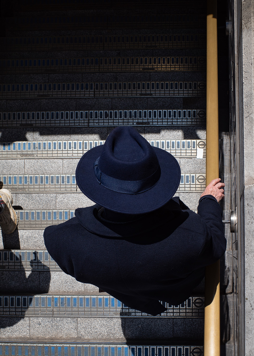 Silhouette of man in hat walks into Oxford Circus Tube - London. Shot from above.